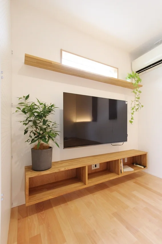 壁掛けテレビと木製シェルフのある洋室
