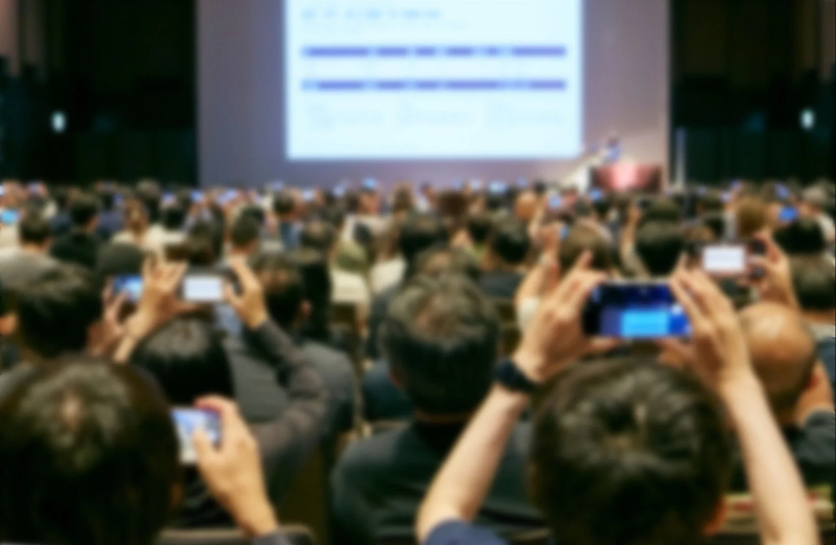 多くの聴衆がスマートフォンを構えて登壇者を撮影している様子
