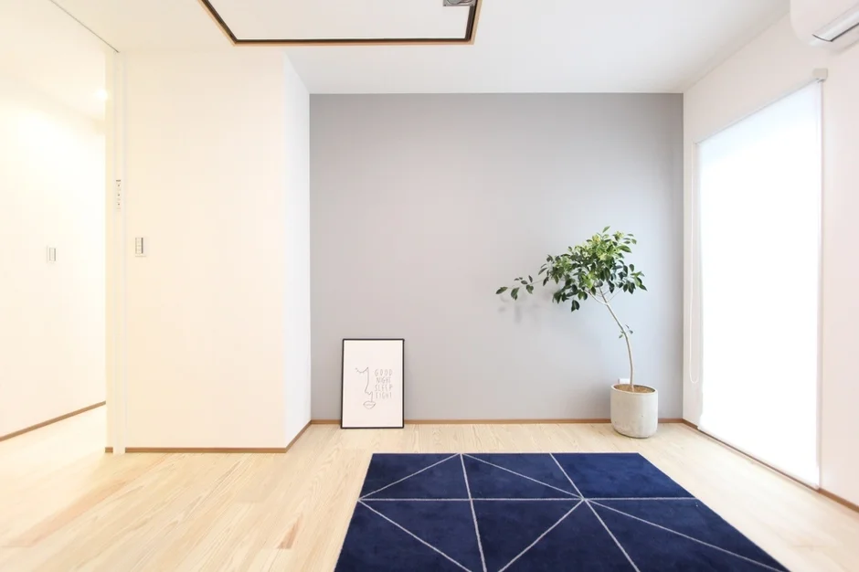 明るい木目のフローリングにネイビーの幾何学模様ラグが敷かれたモダンな部屋