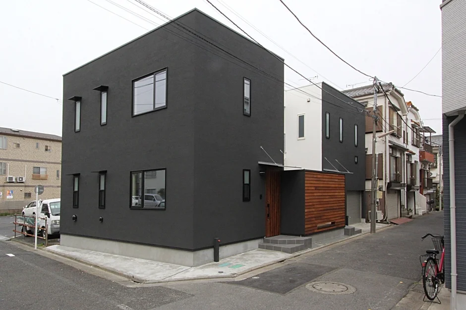 現代的な黒い外壁の住宅が街角に建つ風景