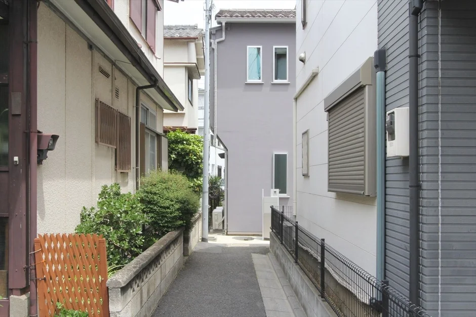 住宅街の細い路地が奥へと続く光景です。