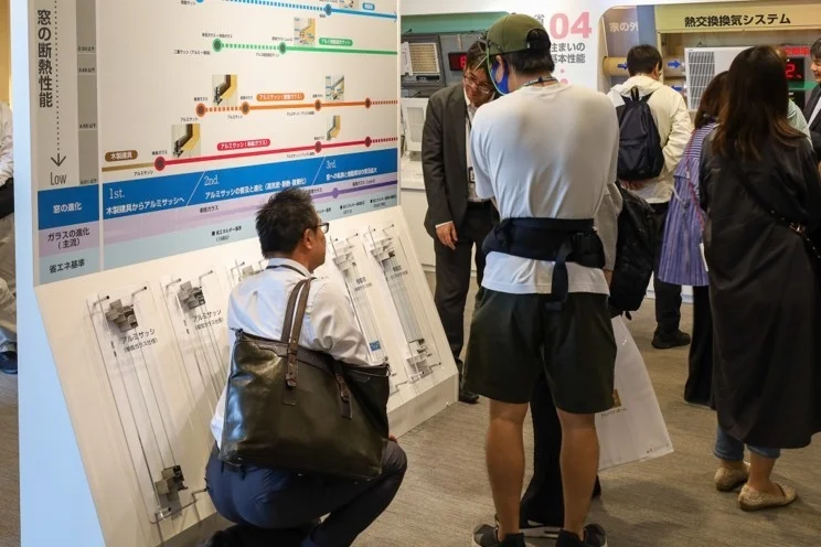 窓の断熱性能やサッシの進化に関する展示を見学する来場者