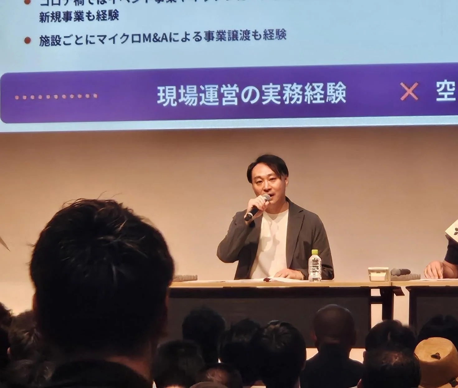 マイクを手に聴衆に語りかける男性の講演風景