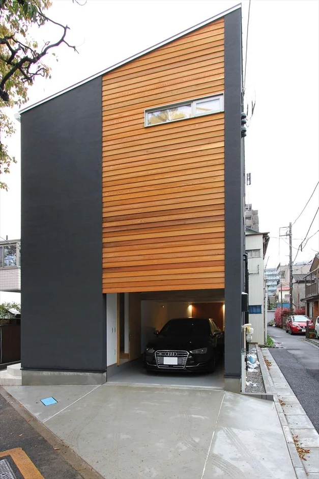 ダークグレーと木製サイディングのコントラストが特徴的な、都市の狭小地に建つモダンな住宅