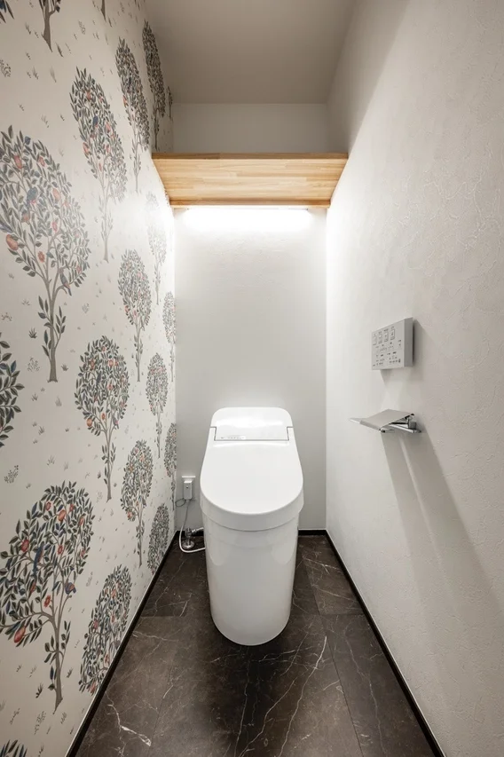 壁の片面に木と果実の柄のアクセントクロスが施された、清潔感のあるモダンなトイレルーム
