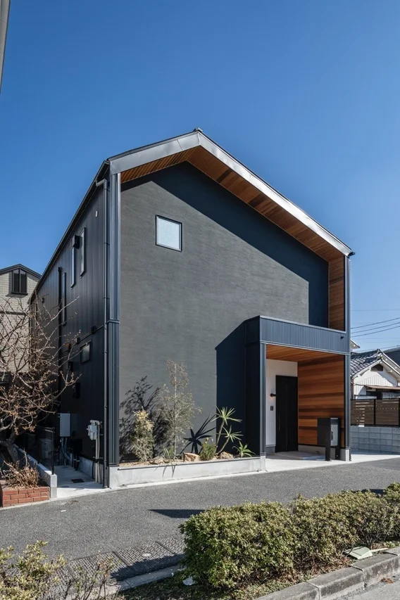 ダークグレーの外壁と木材のアクセントが特徴的なモダンなデザインの住宅