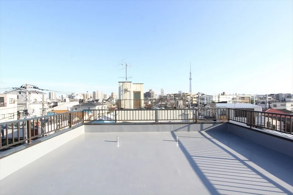 広々とした屋上からの眺望です。遠くには東京スカイツリーが見え、手前には住宅街が広がっています。晴れた日の開放的な景色が特徴です。