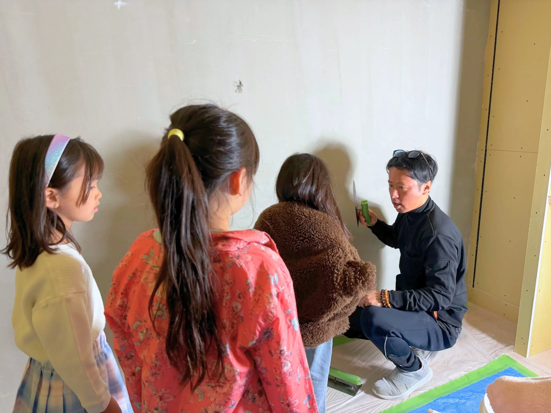 男性が壁塗り実演、子供たちが見学