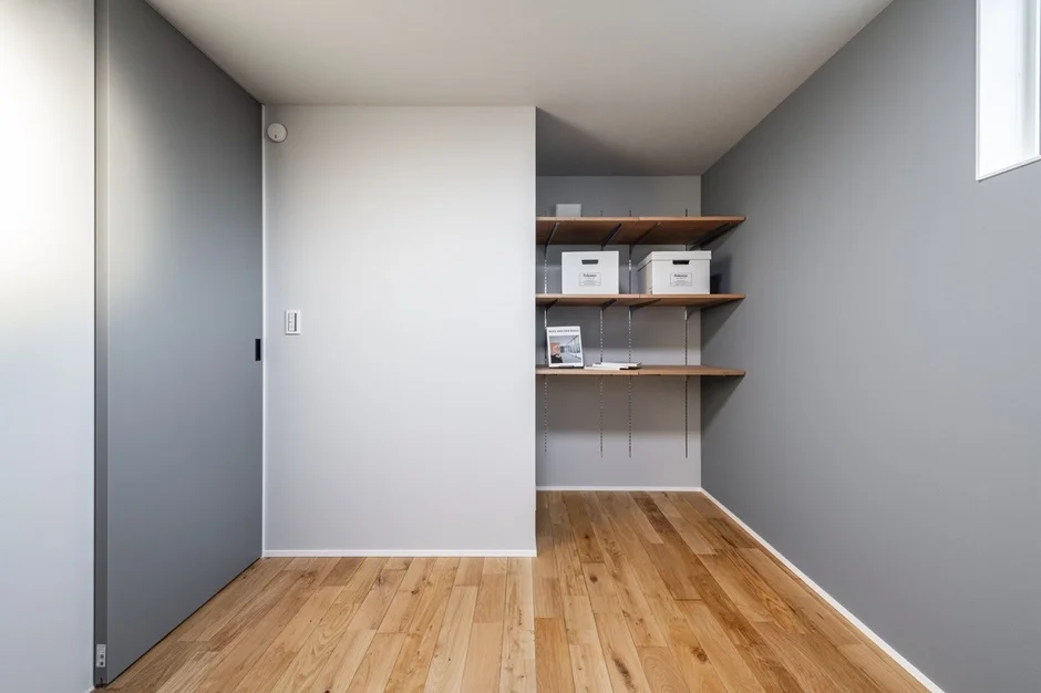 明るいグレーの壁と木製フローリングのシンプルな部屋