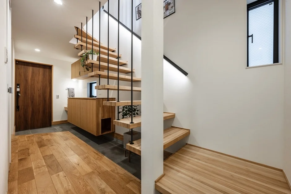 明るい木製フローリングと白い壁が特徴のモダンな住宅の玄関ホール