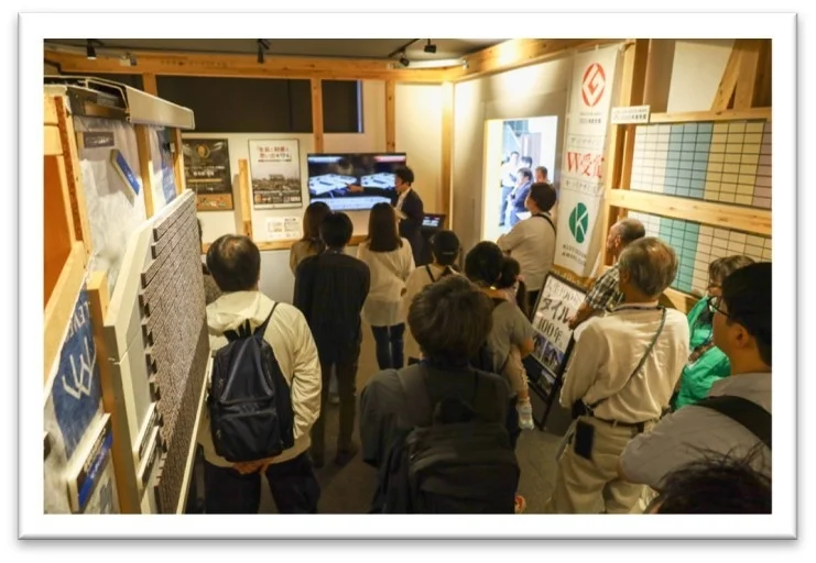 屋内の展示スペースで建築関連の展示を見学する人々