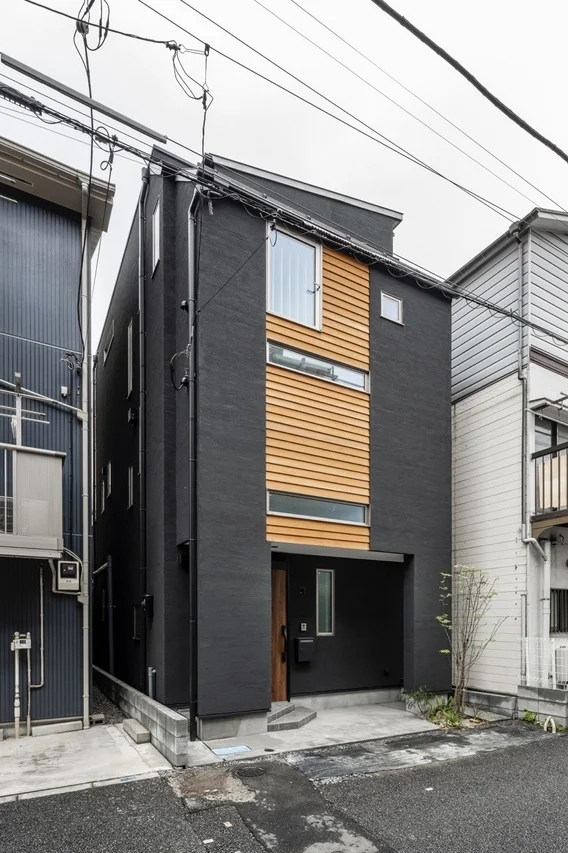 ダークグレーの外壁と木材のアクセントが特徴的なモダンな狭小住宅