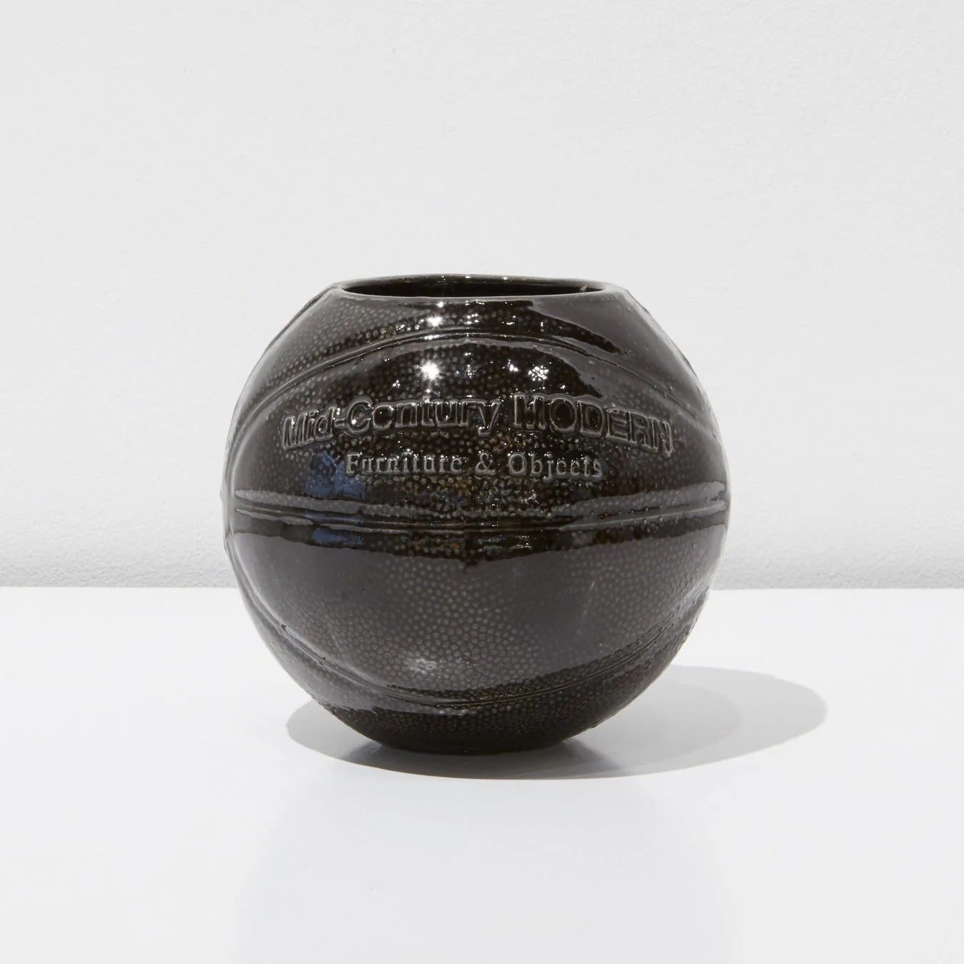 バスケットボールの形をした黒い光沢のある陶器製の花瓶です。