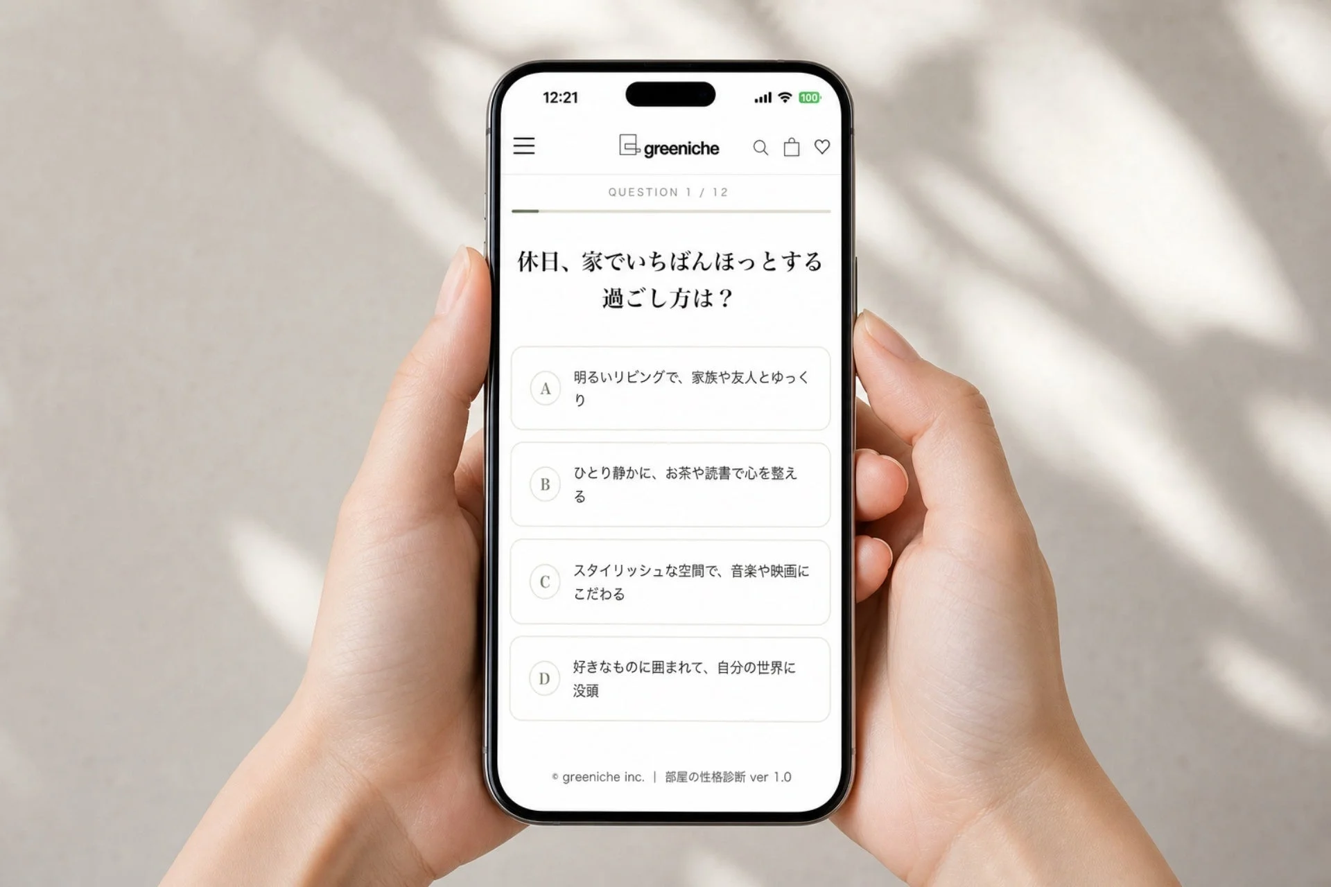 両手がスマートフォンを持ち、画面にはgreenicheアプリの「部屋の性格診断」が表示されている。休日のリラックスした過ごし方に関する質問と4つの選択肢(A〜D)が日本語で提示されており、ユーザーが回答を選んでいる場面を捉えた画像です。