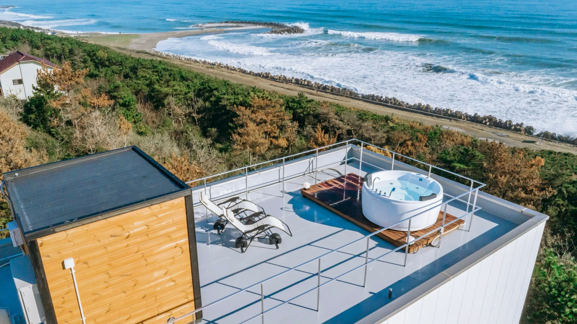 海と森に囲まれた絶景のロケーションにある宿泊施設の屋上テラス。開放的なジャグジーとラウンジチェアが設置されており、青い空と広がる海を眺めながら贅沢なひとときを過ごせます。