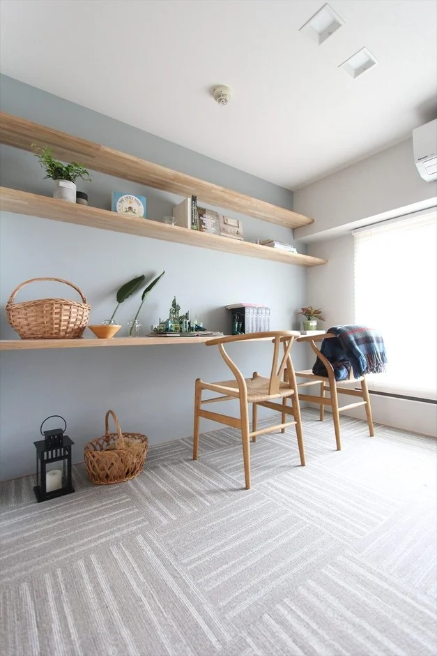 水色の壁と木製シェルフが特徴の明るい部屋