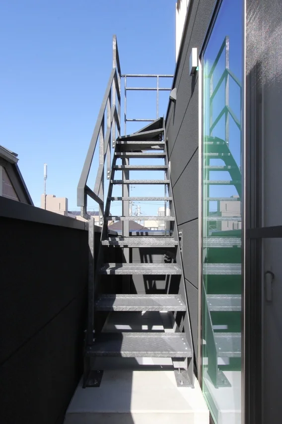晴れた青空の下、建物の側面に取り付けられた金属製の屋外階段