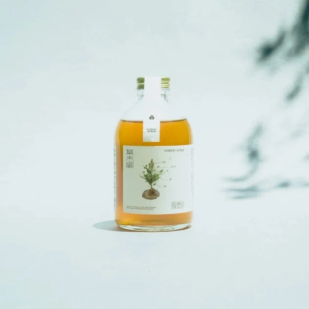 白い背景に置かれた「FOREST SYRUP」と書かれたボトル飲料