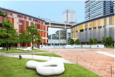 現代的な建物に囲まれた開放的な広場と芝生が広がる都市空間
